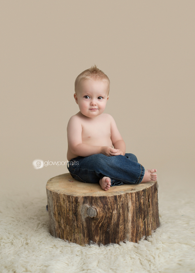 baby boy sitting on stump with jeans on