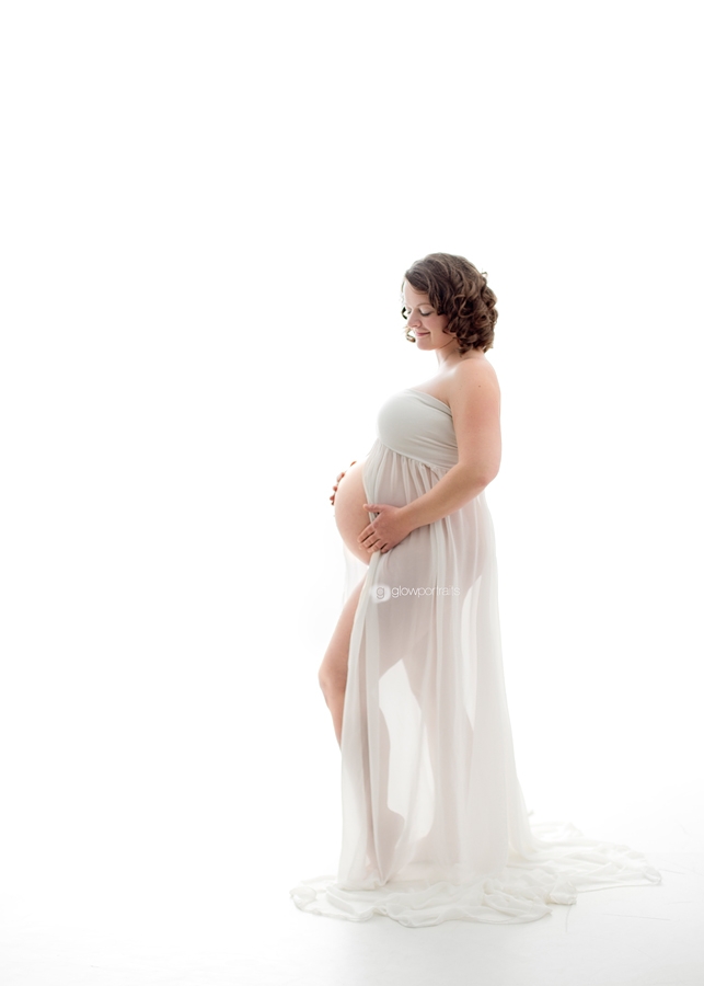 standing in white gown maternity portrait