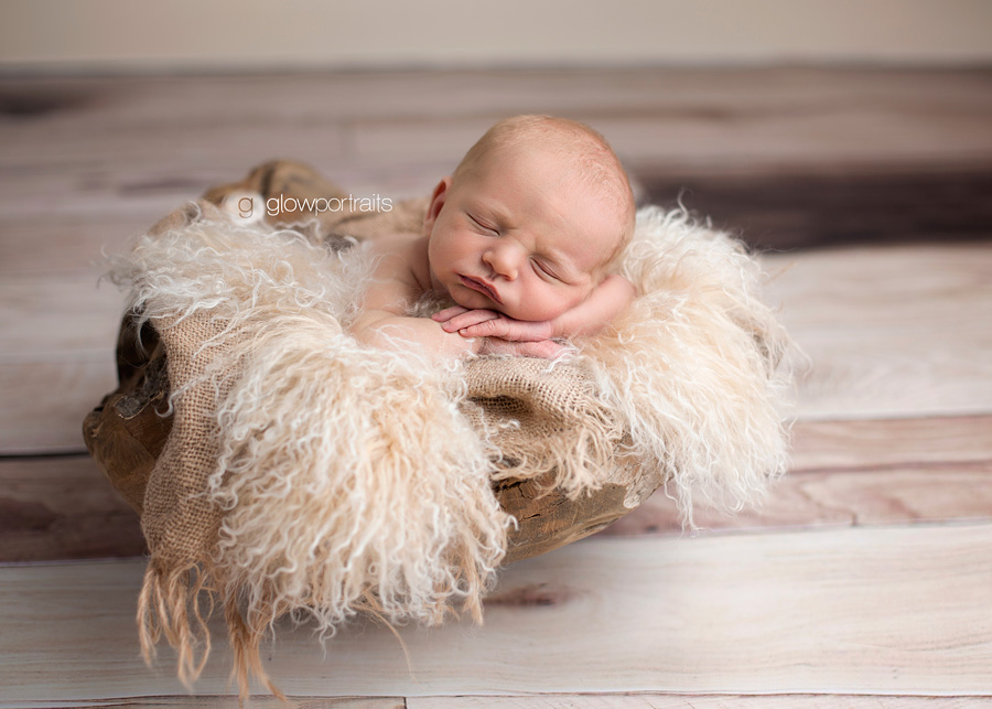 newborn in wooden bowl with fur