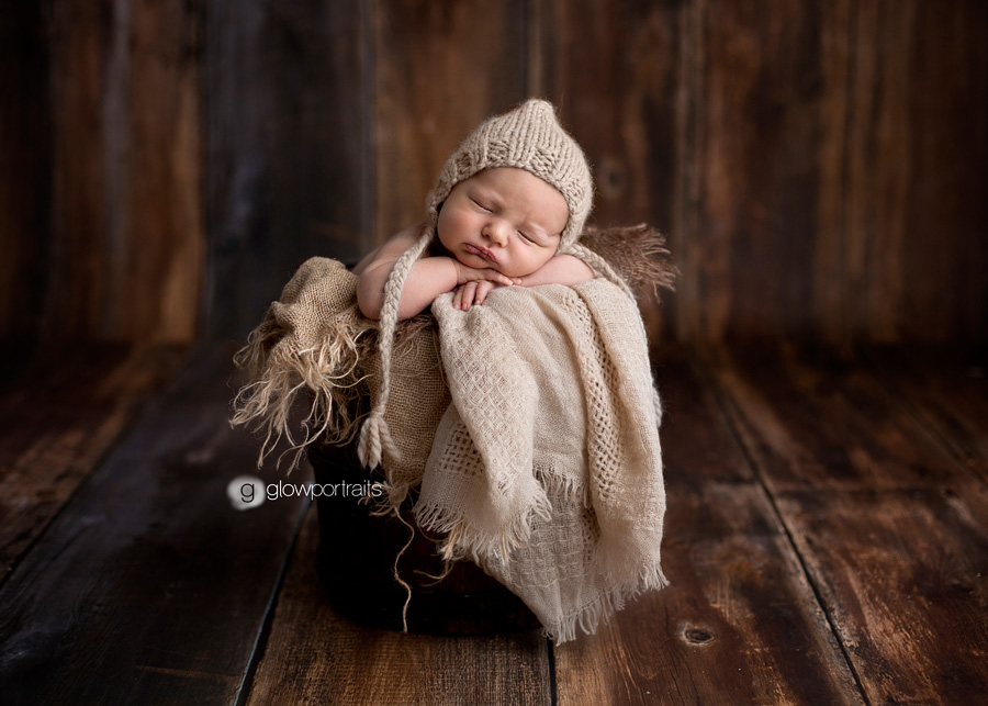 newborn with bonnet in bucket